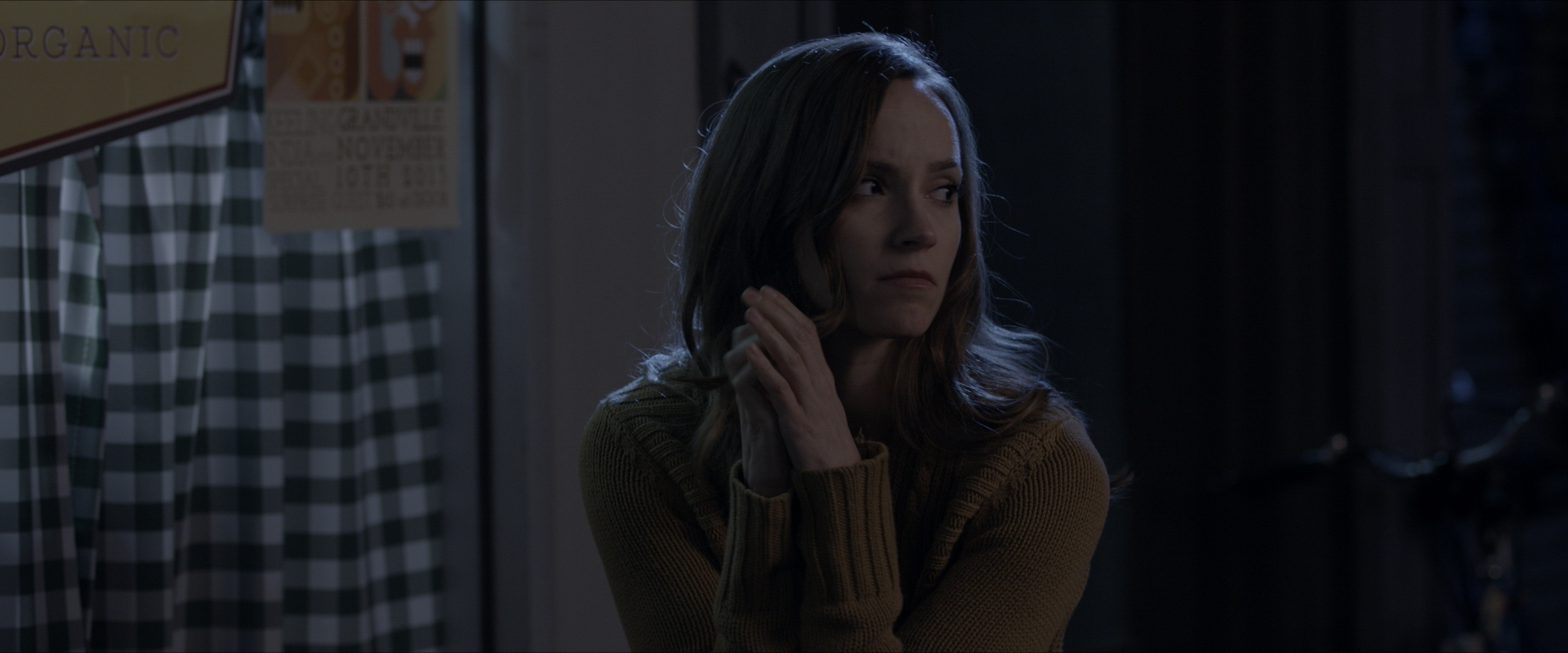 A woman looks off sadly from Believe